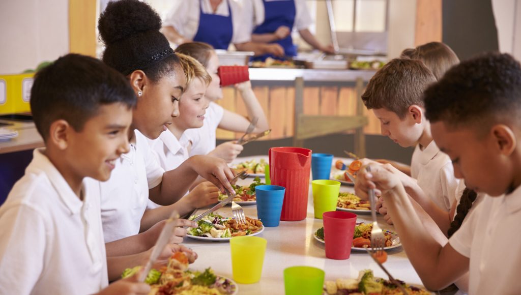 Primary school kids eating at a table in school cafeteria