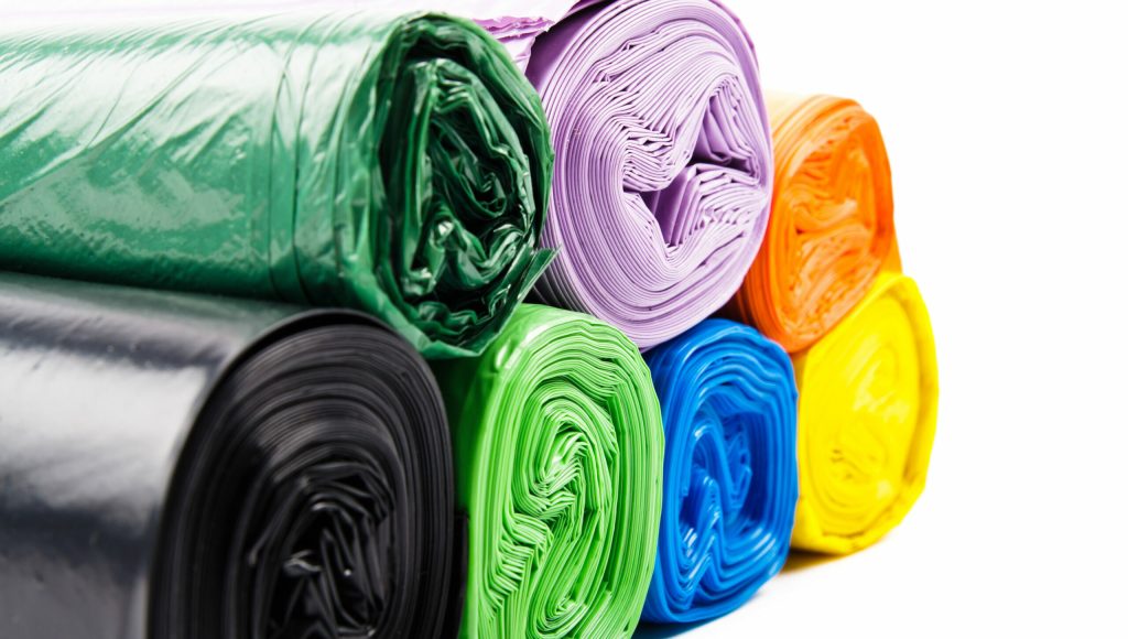 Colored garbage bags on white background