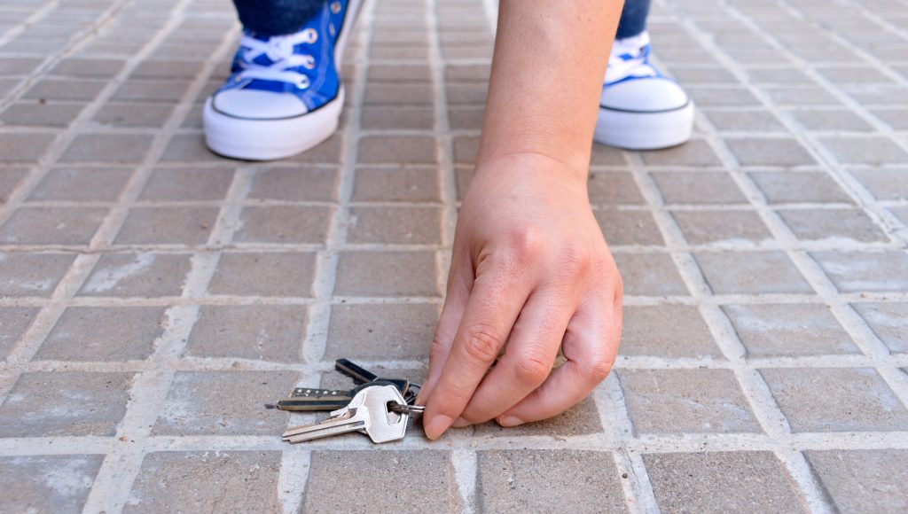 cropped shot of a young finding the keys in the street sidewalk