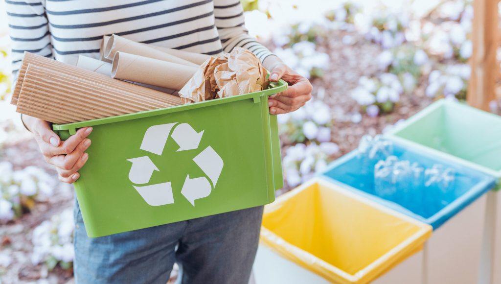 Activist taking care of environment during sorting paper waste to proper recycling bin on terrace