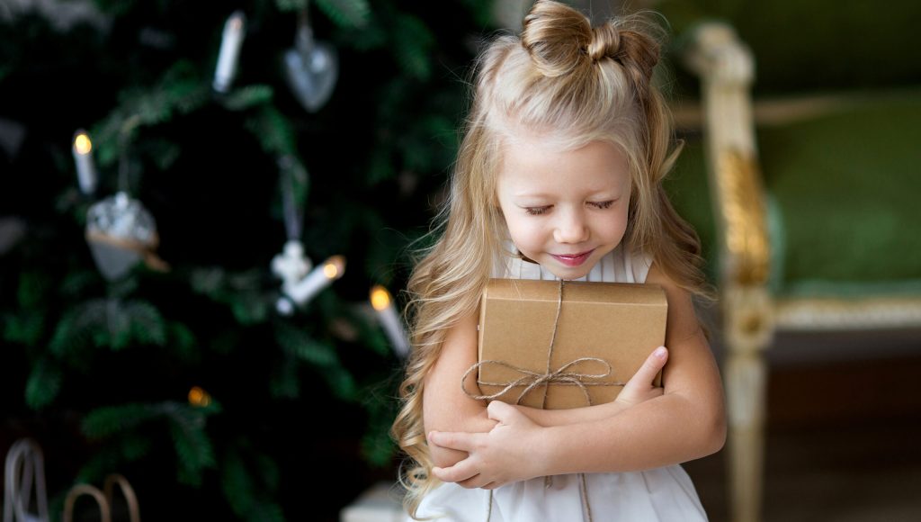 Happy little smiling girl with christmas gift box. Merry Christmas and Happy Holidays.