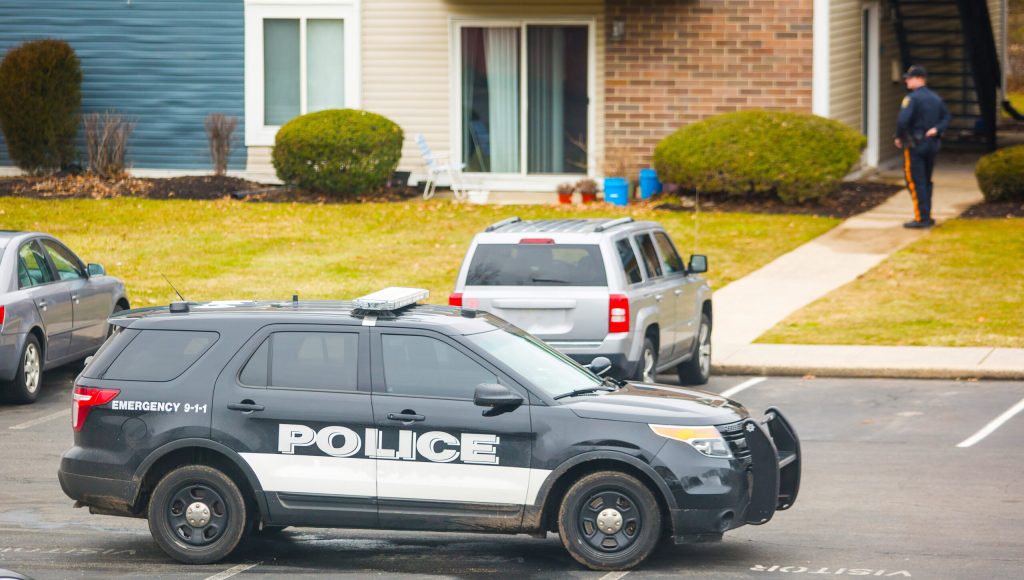 Police car parked in neighborhood with policeman outside