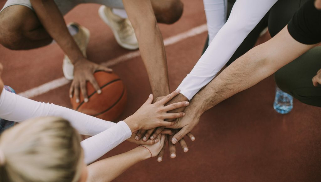 Overhead view of basketball team holding hands over court