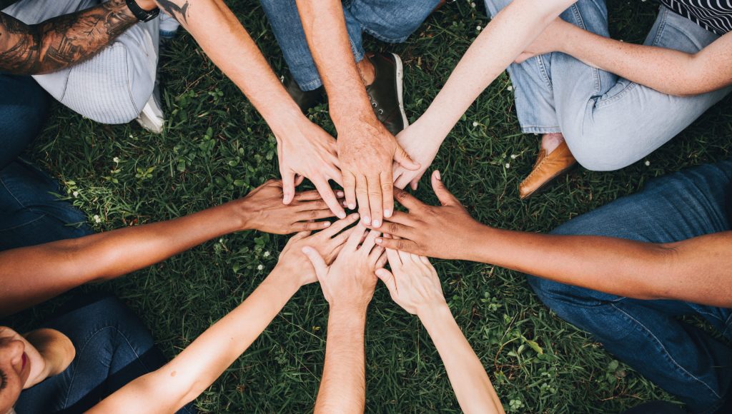 People stacking hands together in the park
