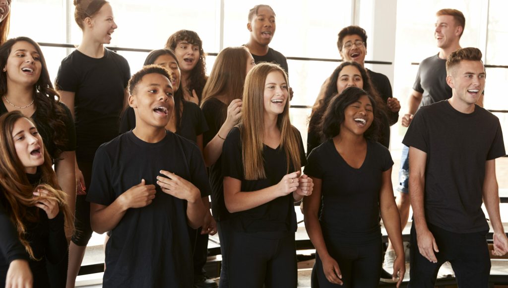 Male And Female Students Singing In Choir At Performing Arts School