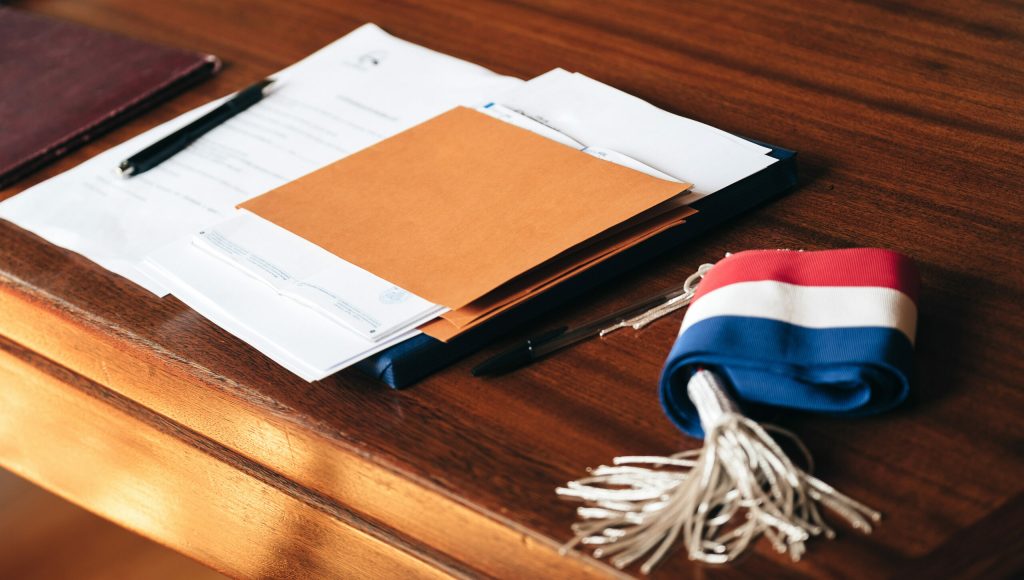 Documents placed on the table of a town hall, with a mayor's sca