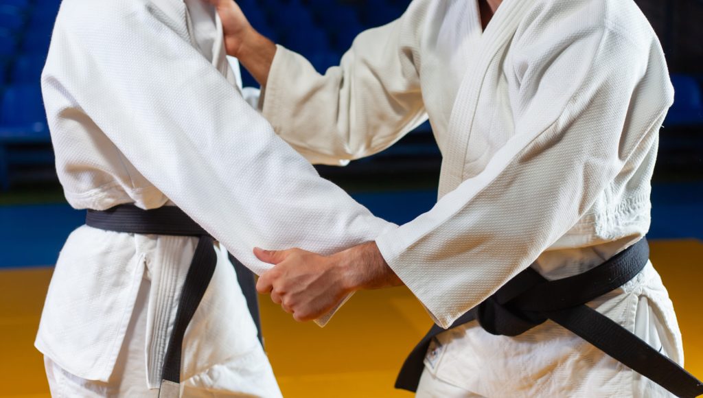 Martial arts. Sparing Portners. Sport man and woman in white kimono train judo captures in the sports hall. Crop photo
