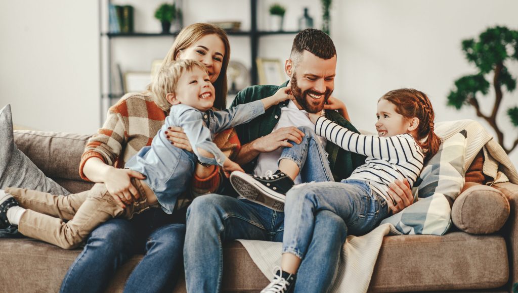 happy family mother father and kids at home on the couch