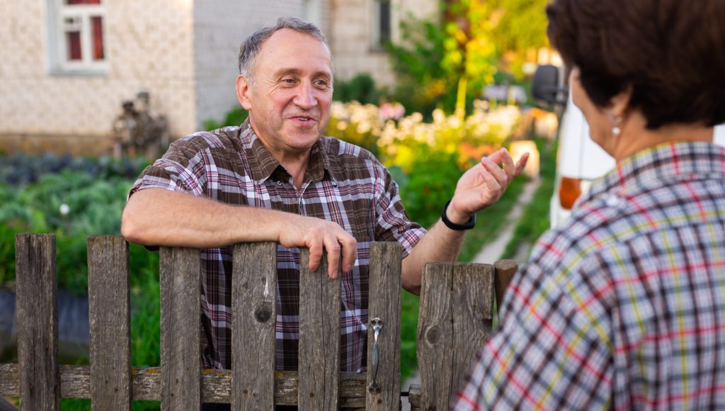 neighbors middle aged man and woman chatting near the fence in the village